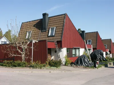 Före: rad av kedjehus med röda gavlar och bruna betongpannor, presenning på marken