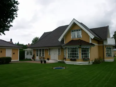 Efter: gul villa med mörkbrunt tak och grön gräsmatta, sedd från sidan