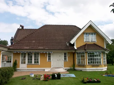 Före: gul villa med blekt, rödbrunt och smutsigt pannetak sett framifrån, arbete pågår på taket