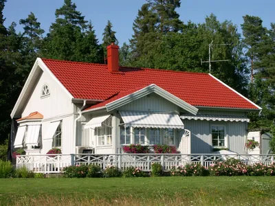 Efter: vit villa med markiser och färdigbehandlat tak i klarrött, sedd från gräsmattan