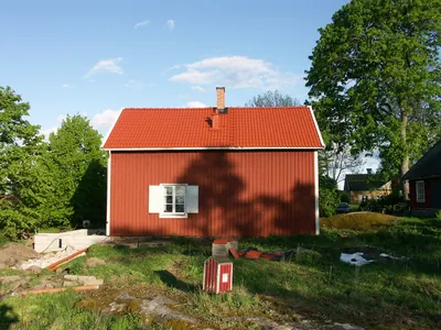 Efter: litet rött hus med färdigbehandlat tegelrött tak, fotat från sidan