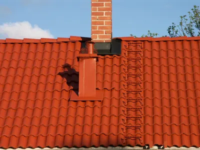 Efter: närbild på tegelrött tak med tegelskorsten och nymålad ventilationshuv