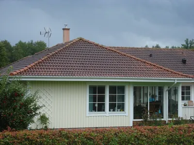 Före: husets hörn med skorsten och urblekta betongpannor på ett valmat tak