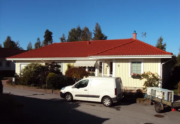 Gulpanelad enplansvilla med nybehandlat tegelrött tak och vit skåpbil på uppfarten