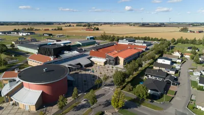 Efter: drönarbild över skolområdet i Vara med färdigbehandlade tak och åkrar i bakgrunden
