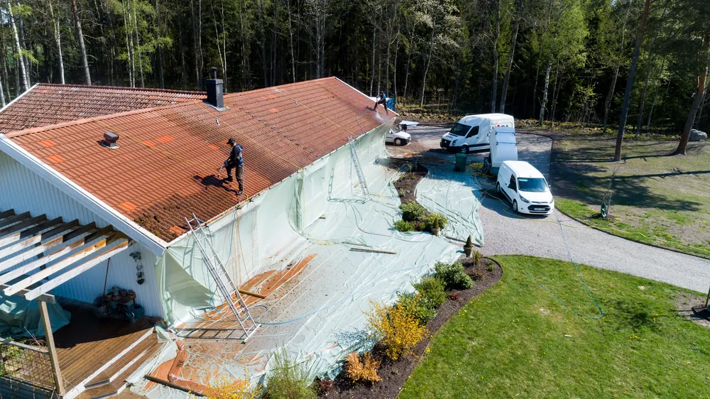 Drönarbild av en villa där taket tvättas med högtryck och fasaderna är täckta med plast